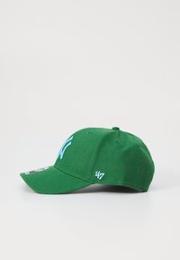 Grønn baseballcap laget av stoff med buet skygge. Har blå brodert logo og detaljer. Inkluderer et lite hvitt merke på siden.