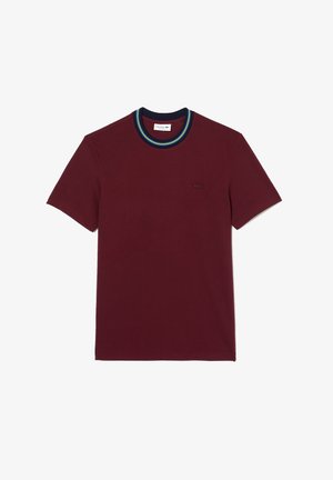 Bordeaux'npunainen puuvillainen T-paita, jossa on pyöreä pääntie ja sinivihreä raidallinen kaulus. Rinnassa hillitty logo. Lyhyet hihat.