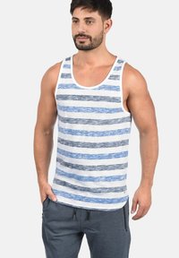 Stripet tanktopp i hvit, blå og mørkegrå; bomullsmateriale; avslappet passform; brede armhull; synlige sømmer langs kantene.