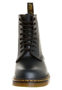 Botín de piel negra con cordones, de tobillo, con puntera redondeada, ojetes de metal y suela de goma marrón. Presenta una lengüeta en el talón.