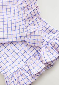 Svetloružová látka s modrým mriežkovým vzorom, vybavená nažehlenými volánmi. Materiál pôsobí textúrovane a mäkko, vhodný na bežné nosenie.