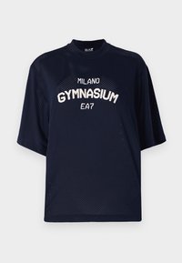 Námorníckomodrá sieťovaná tričko s krátkymi rukávmi. Na prednej strane sa nachádzajú biele nápisy "MILANO GYMNASIUM" a "EA7". Voľný strih, priedušná tkanina.