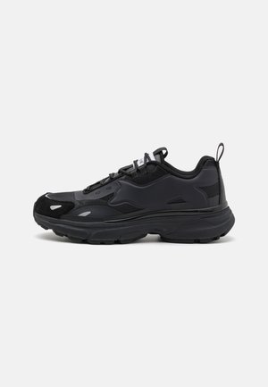 Zapatilla de running negra con un upper texturizado, acentos sintéticos lisos, suela gruesa y detalles reflectantes. Presenta un diseño con cordones y una lengüeta.