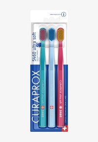 Trzy szczoteczki do zębów w opakowaniu: jedna turkusowa, jedna jasnoniebieska i jedna różowa. Każda ma miękką główkę z kolorowymi, zaokrąglonymi włoskami.