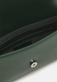 Zelená kožená kabelka na ruku se hladkým povrchem, vybavená stříbrným uzávěrem na patent a vnitřní kapsou na zip pro bezpečné uložení.