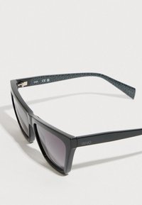 Fekete műanyag napszemüveg téglalap alakú kerettel, átmenetes lencsékkel és texturált fekete szárakkal, melyeken logó található. CE jelöléssel.