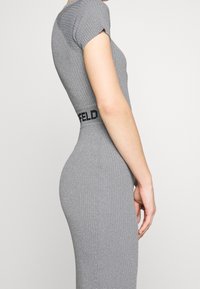 Abito grigio a coste con maniche corte e silhouette aderente. Presenta una vita nera con marchio. Tessuto liscio con una leggera lucentezza.