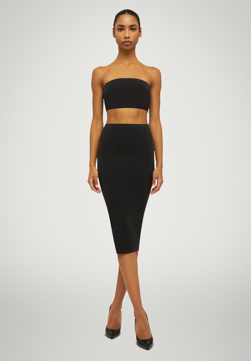 Ensemble noir deux pièces comprenant un crop top sans bretelles et une jupe midi ajustée. Texture lisse avec un design minimaliste et une coupe à mi-genoux.