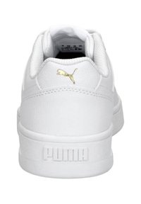 Sneakers bianchi in pelle con colletto imbottito, linguetta testurizzata e logo Puma dorato sul tallone. Suola piatta in gomma con branding impresso.