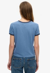 Jasnoniebieska koszulka z krótkim rękawem o kontrastowym granatowym wykończeniu dekoltu i rękawów. Miękka tkanina, luźny krój oraz metka z tyłu.