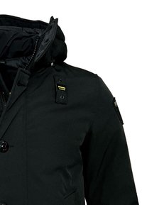 Svart jacka med dragkedja framtill, dubbla knapplås och huva. Materialet är slätt med en elegant design. Märkets etikett synlig.