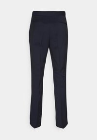 Pantalon bleu marine foncé sur mesure avec poches passepoilées à l’arrière, vu de dos sur fond blanc.