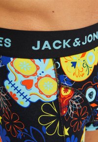 Bunte Boxershorts mit detaillierten Blumen- und Schädelmustern auf schwarzem Hintergrund. Der elastische Bund trägt "JACK & JONES" in Hellblau.