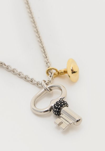 Ασημένιο κολιέ με μενταγιόν σε σχήμα κλειδιού, με μαύρες λεπτομέρειες και ένα μικρό χρυσό γούρι.