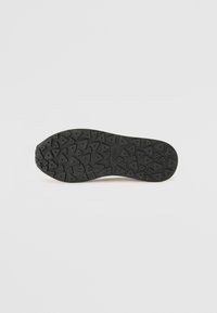 Black rubber shoe sole with a textured pattern of triangular lugs for grip. Features the logo "HUGO" near the center.