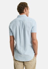 Korte mouwen, lichtblauw shirt van linnen met een button-down kraag en een achterkant met plooidetail, gecombineerd met geborduurde crèmekleurige broek.