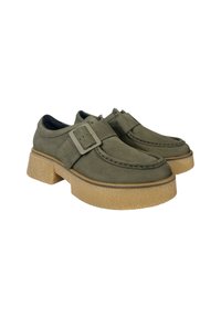 Des chaussures en daim vert avec une semelle plateforme robuste de couleur châtain et un accent de boucle décorative. Bout rond et détails cousus sur le dessus.