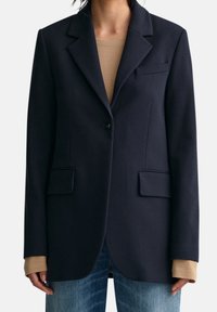 Blazer navy in tessuto testurizzato, con un bottone singolo, rever a taglio, due tasche frontali e una vestibilità sartoriale.