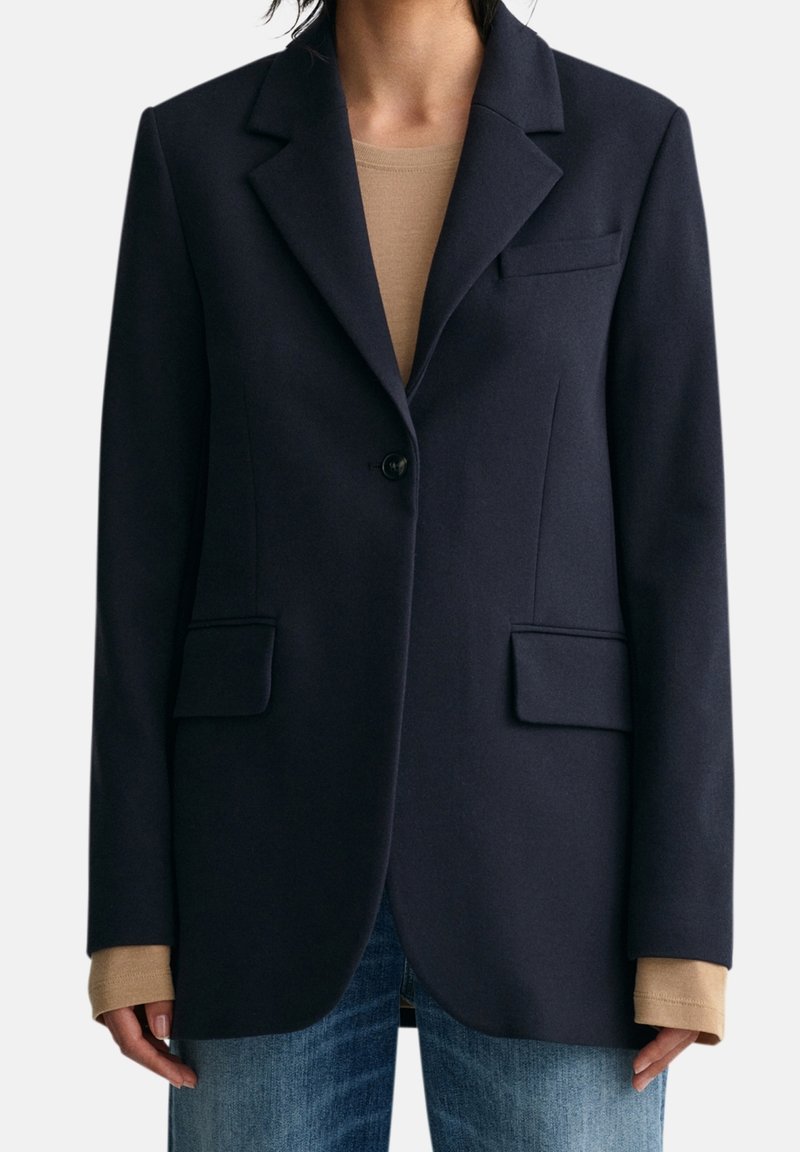 Blazer navy in tessuto testurizzato, con un bottone singolo, rever a taglio, due tasche frontali e una vestibilità sartoriale.