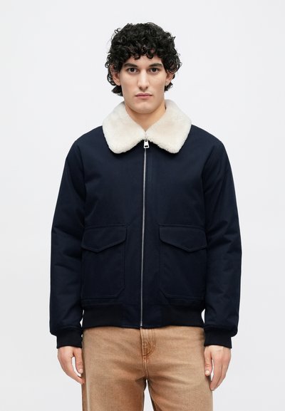 Mornarska bomber jakna z belim ovratnikom iz umetnega krzna, sprednja zadrga, rebrasti manšeti in dvema sprednjima žepoma. Enotna gladka tekstura tkanine.