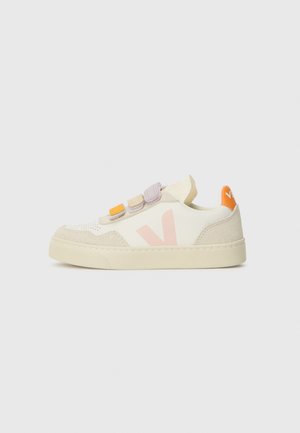 Λευκά sneakers από vegan δέρμα με ανοιχτό καφέ σουέτ λεπτομέρειες, που διαθέτουν παστέλ αυτοκόλλητες λωρίδες και λογότυπο στη φτέρνα. Στρογγυλή μύτη σχεδίασης.