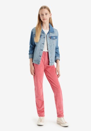 Τζάκετ από τζην με μπλε απόχρωση, λευκό μπλουζάκι και ροζ ριγωτό παντελόνι από κορντόροι. Το μοντέλο φοράει λευκά αθλητικά παπούτσια. Απλός, καθημερινός σχεδιασμός ενδύματος.