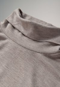 Taupe turtleneck sweater lavet af blødt, elastisk stof; har en foldet krave og glat tekstur med subtile farvevariationer.