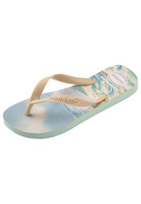 Koppa muovinen flip-flop, jossa on beige hihnat ja vaaleansininen painettu jalkapohja, jossa on aaltojen kuvio. Pohjat ovat mintunvihreät ja karhennetut.