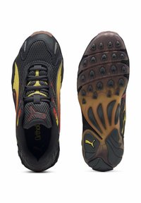 Schwarze atmungsaktive Sportschuhe aus Netzgewebe mit gelben und roten Akzenten, ausgestattet mit einer strukturierten Sohle mit Gummistollen für Traktion und einem gepolsterten Schaft für Komfort.