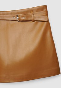 Jupe en cuir marron à la texture lisse, dotée d'une large ceinture avec une boucle en métal. Le modèle est ajusté avec un ourlet évasé.