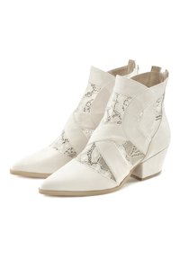 Botas de tobillo beige con punta afilada, que presentan una mezcla de paneles de ante y encaje, y un tacón bajo cuadrado. El encaje texturizado añade detalle al diseño.