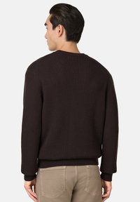 Tmavohnedý rebrovaný sveter s okrúhlym výstrihom a dlhými rukávmi. Mäkkučká, štruktúrovaná tkanina, ktorá je obtiahnutá na páse s rebrovanými manžetami a lemom.