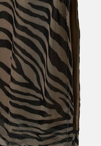 Mesh tank top med et sort og beige zebra-stribet mønster, blød tekstur og en afslappet pasform.