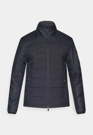 Jachetă căptușită de culoare albastru marin, cu un guler înalt, fermoar frontal și buzunare laterale. Materialul texturat are un model de cusături orizontale pe corp.