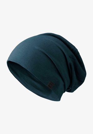 Tume teal värvi nokamüts, mis on valmistatud pehmest kangast, omab kaudset disaini, millel on tekstuuriga voldid ja väike must logo silt küljel.