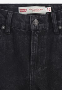Jeans in denim nero con taglio dritto, caratterizzati da un bottone in metallo, tasche frontali e un'etichetta con la scritta "Levi's 551Z™ Authentic Straight."