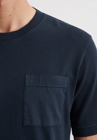 Marineblauwe t-shirt van ribstof, met een borstzak van een gladder materiaal, ronde halslijn en korte mouwen.