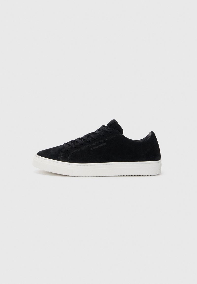 Adidași din suede negru, cu un design low-top, vârf rotund și talpă din cauciuc alb. Prezintă sireturi negre și un branding minim pe lateral.