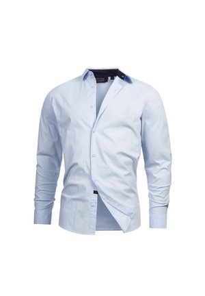 Camisa azul clara de manga larga y botones, hecha de tela de algodón. Presenta un cuello clásico, cierre frontal de botones y un distintivo acento azul marino en el cuello.