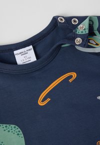 Marine peuter t-shirt met groen en oranje dinosaurusprint, drukknoopjes op de schouder, en maatlabel dat 1,5-2 jaar aangeeft, merk Polarn O. Pyret.