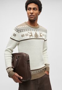 Pletený sveter v krémovo-hnedej farebnej schéme s vianočnými vzormi, doplnený tmavohnedou koženou taškou s dvojitými rúčkami.