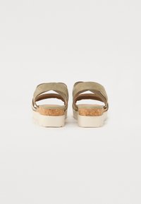Olivengrønne sandaljer med krydsremme, korkmidtsåle og lys gummisål. Har en glat tekstur og minimalistisk design.