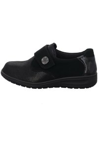 Black shoe with textured upper featuring a reptile pattern, a smooth black strap with a silver snap closure, and a thick sole for support.