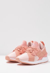 Zapatillas deportivas rosas que presentan una combinación de materiales suaves y texturizados, puntera redonda, parte frontal con cordones, cuello acolchado y una suela intermedia blanca.