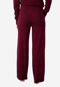 Bordowe szerokie spodnie dresowe z prążkowanym paskiem w talii. Posiadają jedną tylną kieszeń. Miękka tekstura i luźny krój.
