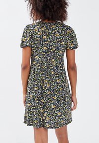 Robe noire à motifs floraux avec des manches courtes, ornée de fleurs colorées jaunes et bleues, en tissu léger, avec une coupe ample et fluide.