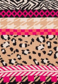 Tejido de punto con patrones audaces: rayas de cebra, manchas de leopardo, pata de gallo y formas geométricas en negro, beige, rosa y crema.