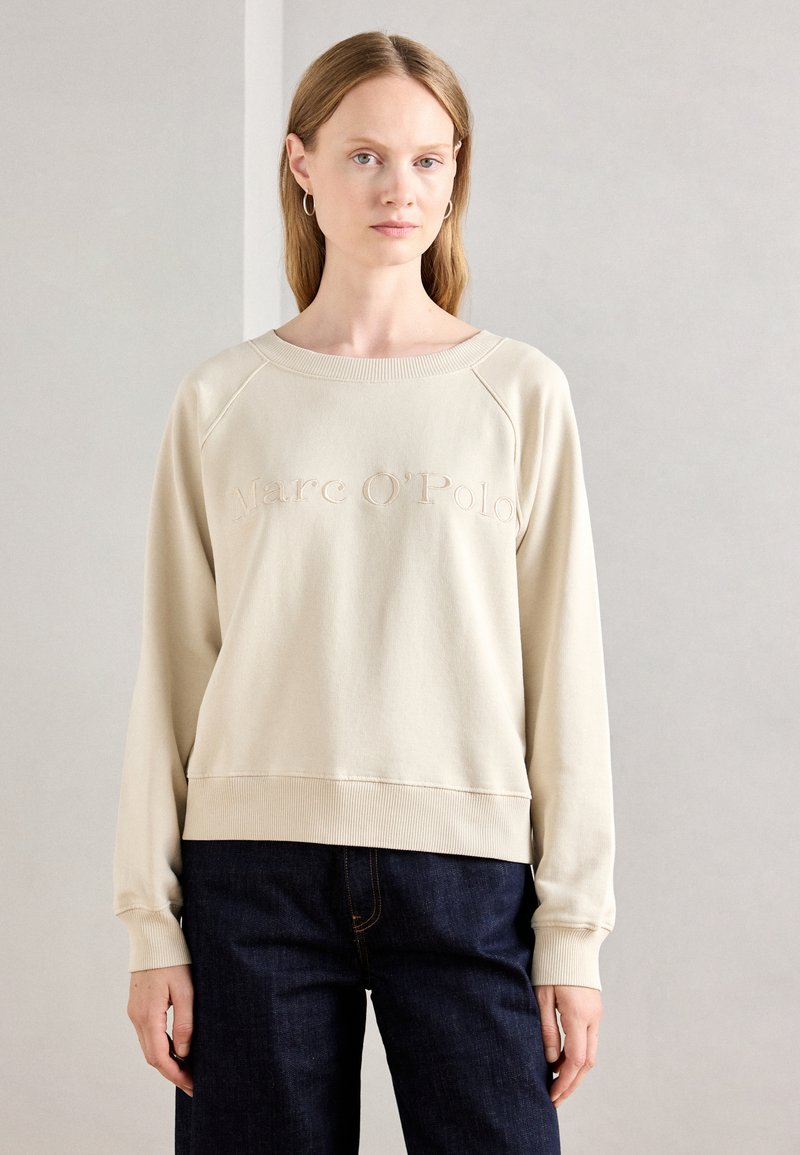 Felpa beige con colletto e polsini a coste. Logo "Marc O'Polo" ricamato sulla parte anteriore. Tessuto morbido e liscio, vestibilità casual.