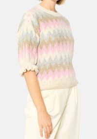 Stickad tröja med ett zickzackmönster i pastellrosa, blått och beige. Puffärmar med volangkant och ribbad fåll. Mjuk textur.