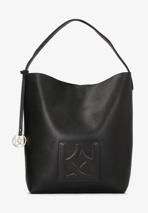 Mustadrik must ületatakse nahast käekott, millel on sile tekstuur, kuju ümarke ja kolm korda ülestõstetud logo silt, millel on riputatud ümmargune kuldne kaelakee.